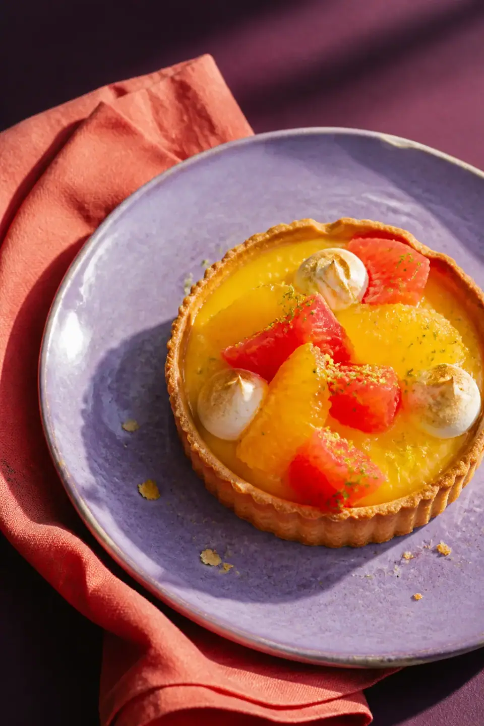 Bright citrus tart on a lavender plate with coral linen
